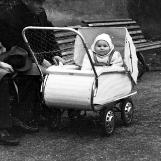 Man and child in stroller sit on park benches.