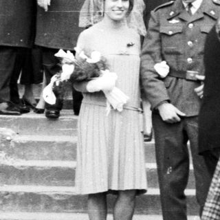 Woman in dress being photographed outside a building.