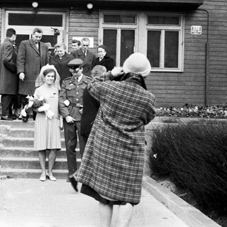 Woman in dress being photographed outside a building.
