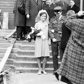 Woman in dress being photographed outside a building.