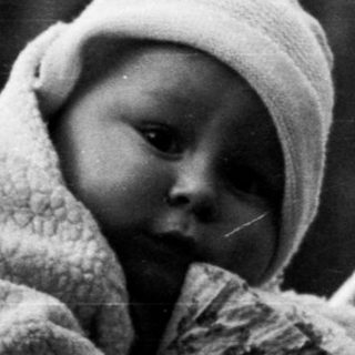 Baby in a vintage pram, monochrome photograph.