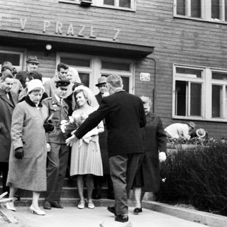 Group gathers outside a building, seemingly welcoming or escorting someone.