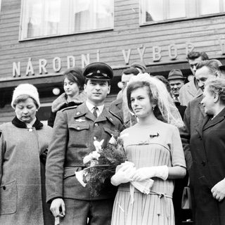 Bride and groom with family outside a building.