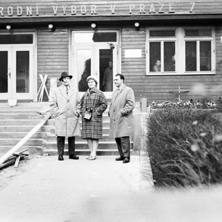 Three people stand outside a building in Prague.