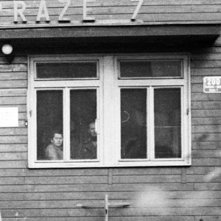 Three people stand outside a building in Prague.