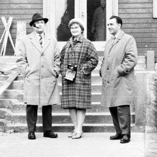 Three people stand outside a building in Prague.