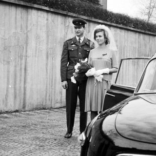 Military officer and bride stand near a vintage Tatra car.