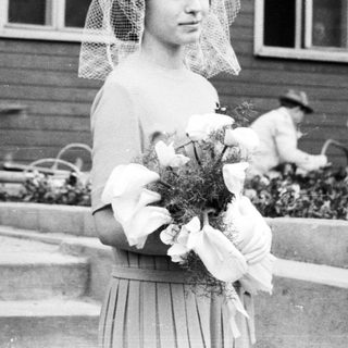 Black and white photo of a bride standing outside a building.