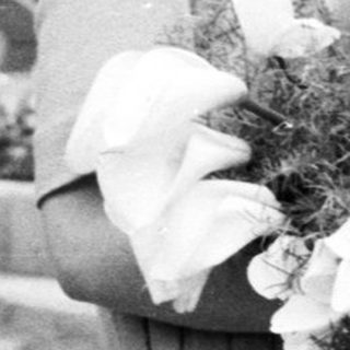 Black and white photo of a bride standing outside a building.