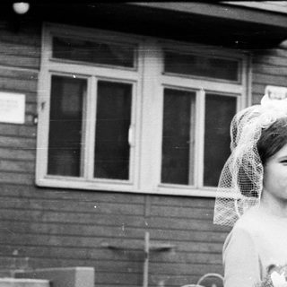 Black and white photo of a bride standing outside a building.