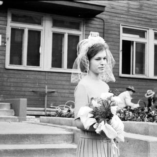 Black and white photo of a bride standing outside a building.