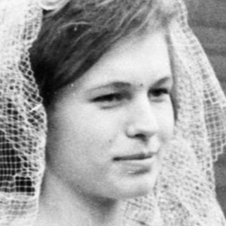 Black and white photo of a bride standing outside a building.