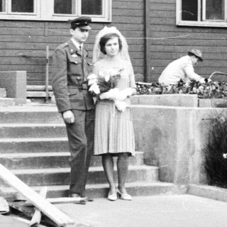 Couple poses for photo during construction in front of building.