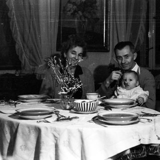 Family seated at a table, with a baby being held.