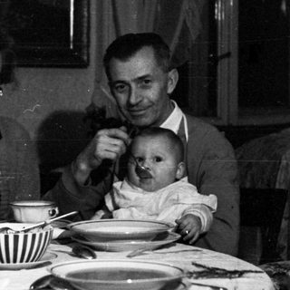 Family seated at a table, with a baby being held.
