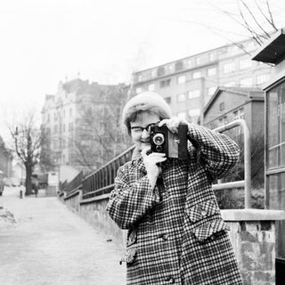 Person takes a photograph on a street in winter.