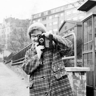 Person takes a photograph on a street in winter.