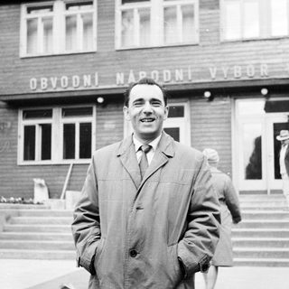 Man smiles in front of a building in Prague.