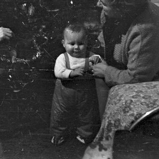 Family gathers near a Christmas tree, vintage photograph.