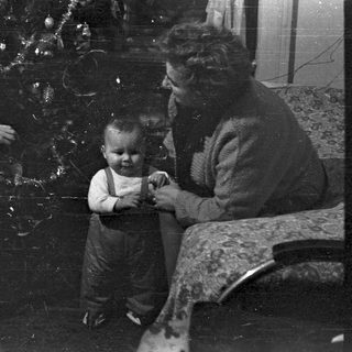 Family gathers near a Christmas tree, vintage photograph.