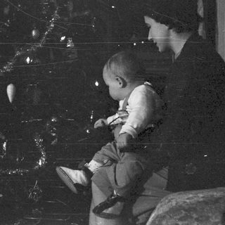 Woman holding a baby near a Christmas tree.