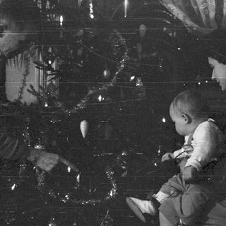 Woman holding a baby near a Christmas tree.