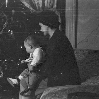 Woman holding a baby near a Christmas tree.