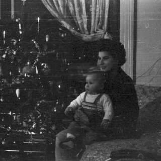 Woman and child seated near a decorated tree.