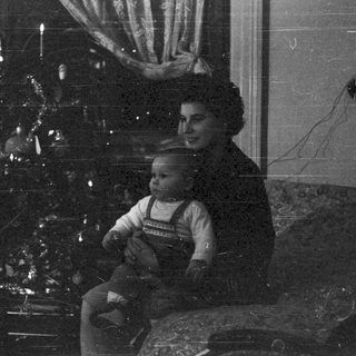 Woman and child seated near a decorated tree.