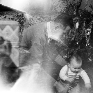 Man and baby near a decorated Christmas tree.