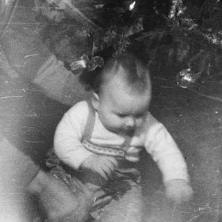 Man and baby near a decorated Christmas tree.