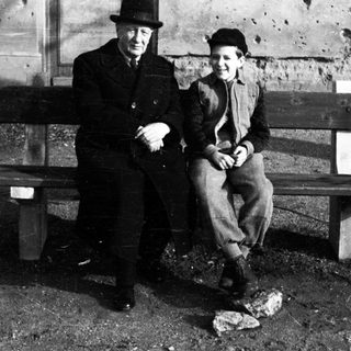 Man and boy seated on a weathered wooden bench.