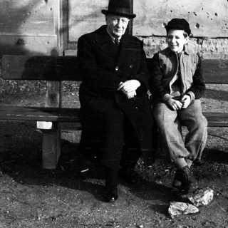 Man and boy seated on a weathered wooden bench.