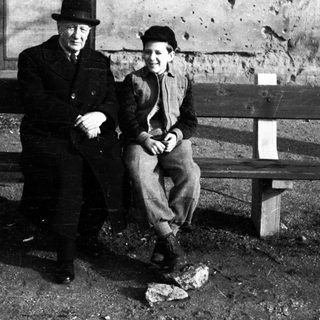 Man and boy seated on a weathered wooden bench.