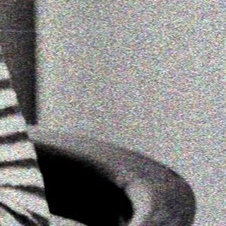 Here's a brief summary of the image: Woman seated, striped shirt, looking downward in a room.