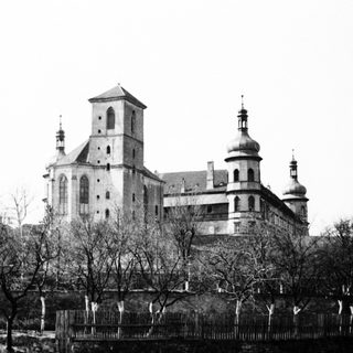 Monastery with towers and domes reflected in water.