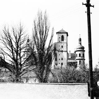 Here's a brief summary of the image: Black and white photo of a church and utility pole.