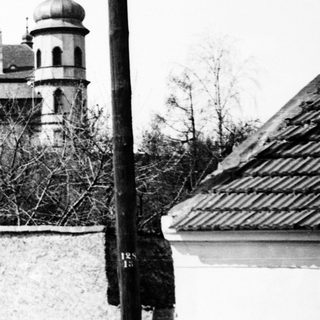 Here's a brief summary of the image: Black and white photo of a church and utility pole.