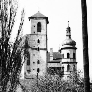 Here's a brief summary of the image: Black and white photo of a church and utility pole.