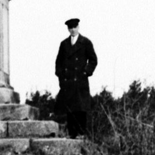 Monument stands in a field, a person nearby.