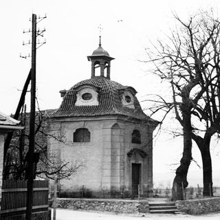 Here's a brief summary of the image: Stone chapel with tower stands amidst bare trees.