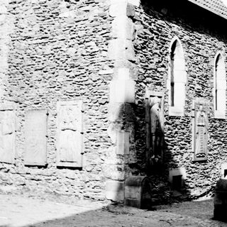 Stone building with arched windows and tombstones in foreground.