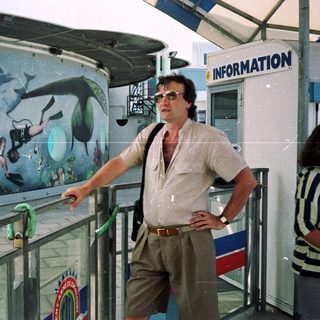 Man stands near a mural depicting divers and marine life.