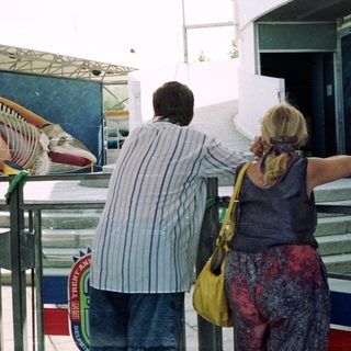 People view a mural outdoors in a public space.