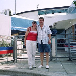 Couple posing outside a building with a sign.