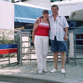 Couple posing outside a building with a sign.