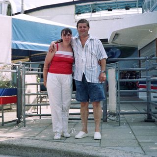 Couple posing outside a building with a sign.