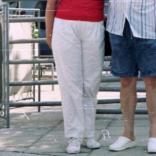 Couple posing outside a building with a sign.