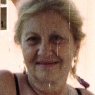 Woman stands on a balcony, wearing casual clothing.
