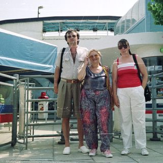 Three people stand near a building entrance, outdoors.